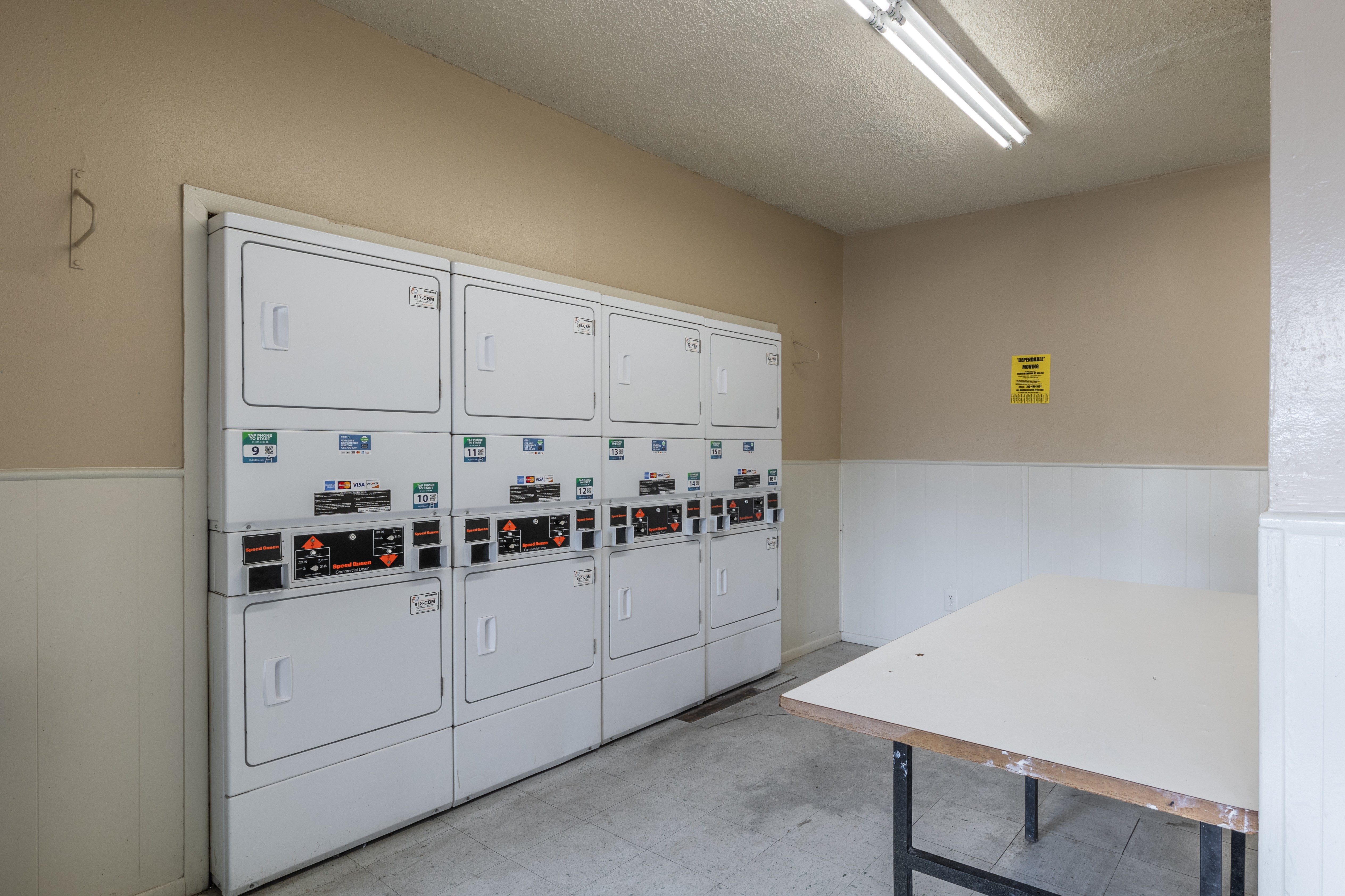 A row of washing machines are lined up in a laundry room.